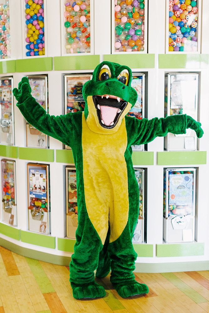 Allie the Alligator mascot waving in the office's prize-machine area