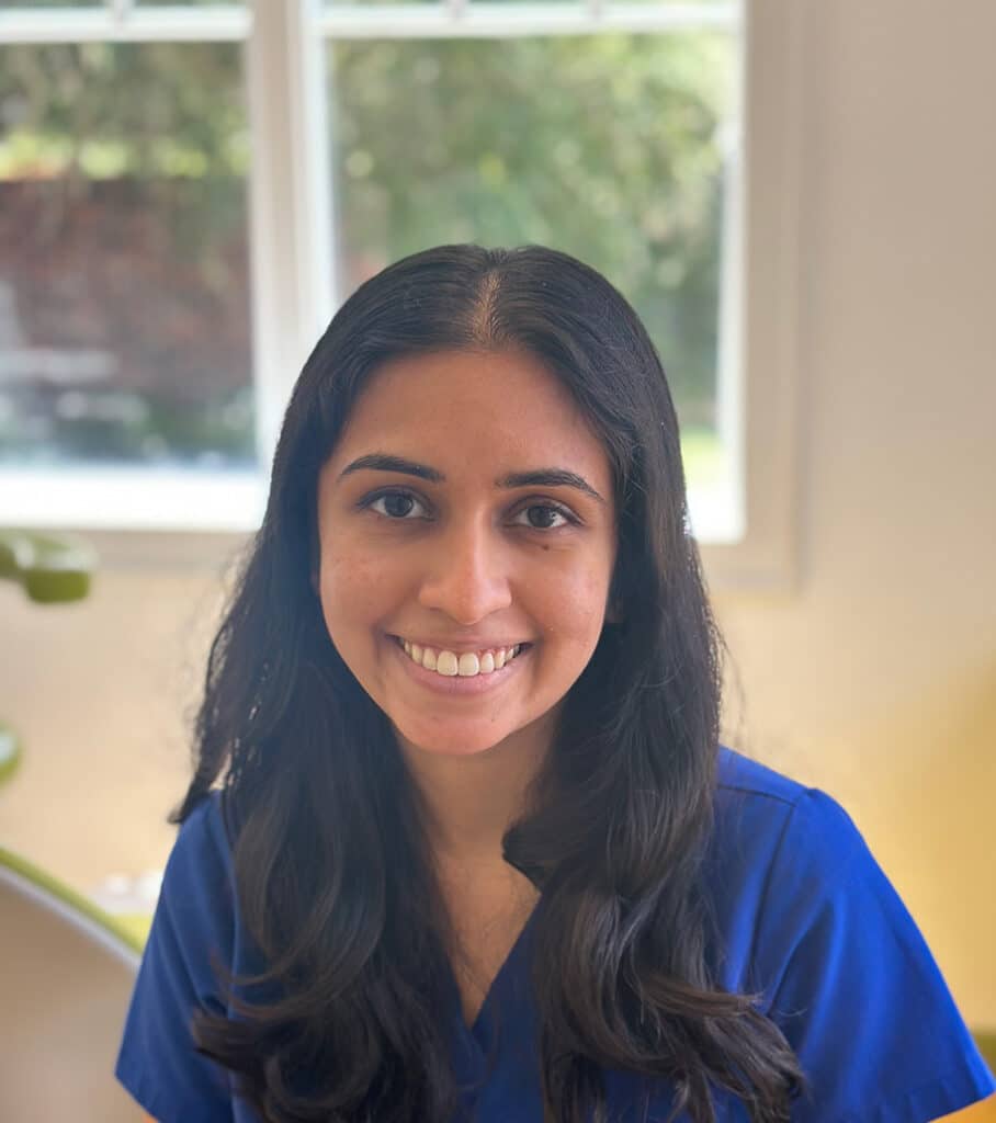 Dr. Sonia Bhutra in blue scrubs, smiling in the office